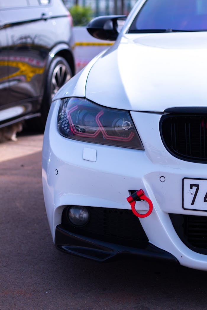 Detailed view of a white cars front headlight and bumper in daylight, ideal for automotive themes.
